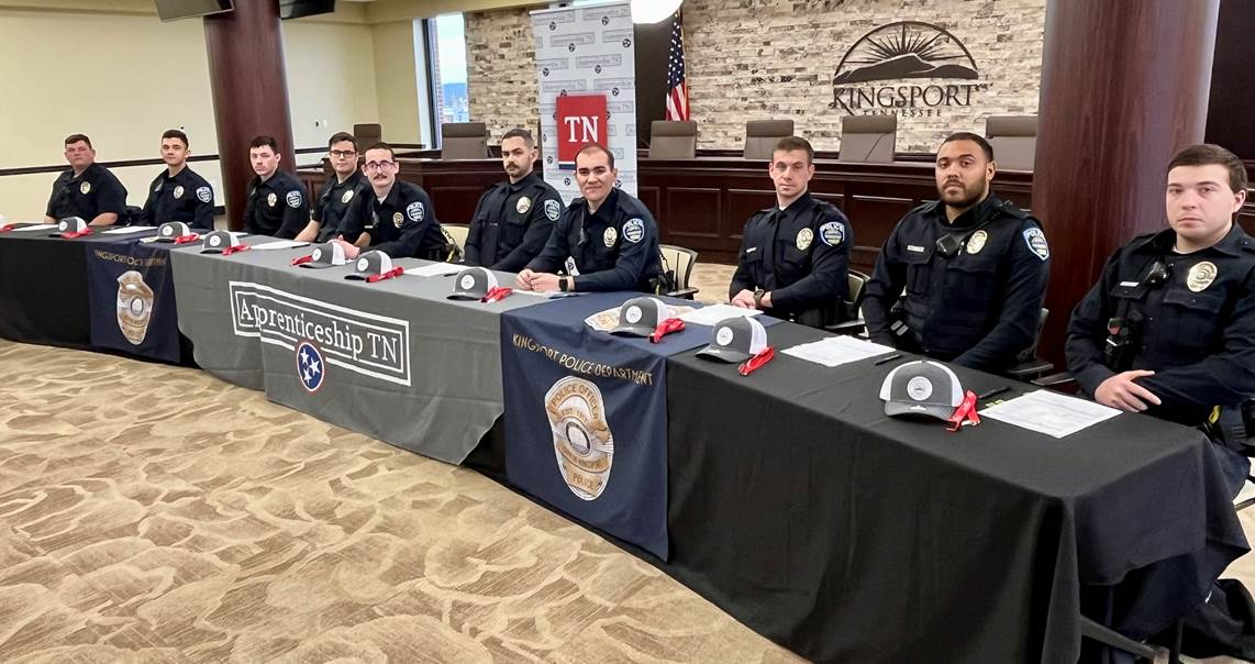 A group of people in uniform sitting at a table  Description automatically generated with low confidence