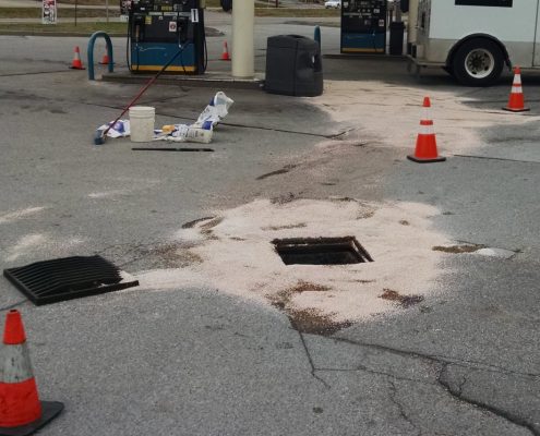 Hazmat absorbing fuel spill in parking lot