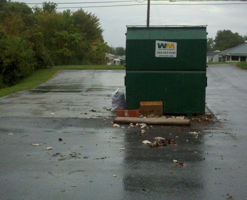 trash overflowing out of parking lot dumpster