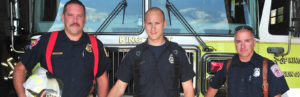 three firefighters in front of truck